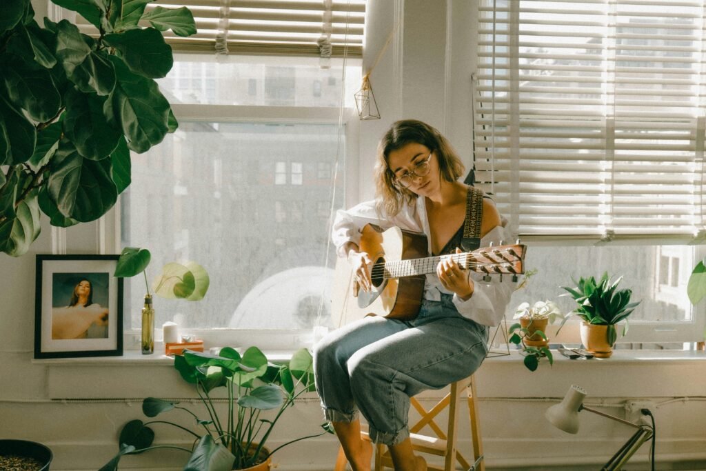 Minimalist wooden desk setup with a book and acoustic guitar in soft morning light