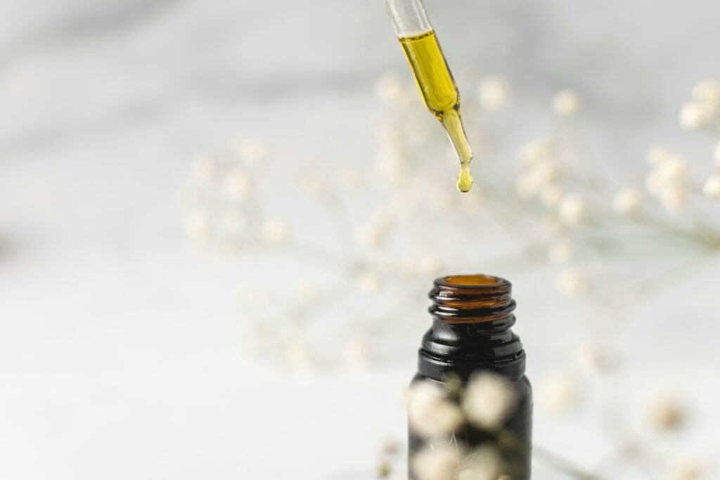 A dark glass bottle releasing a single drop of natural botanical extract onto a rustic linen cloth