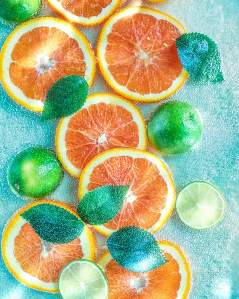 A clear glass bowl filled with fresh summer fruit slices served outdoors in natural shade