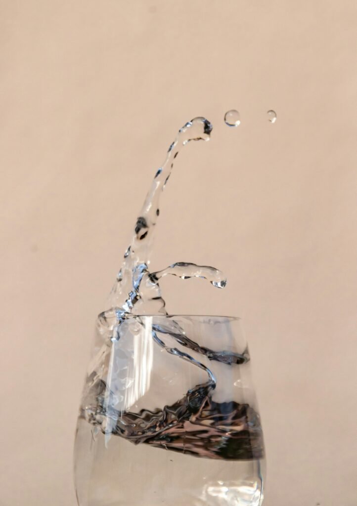 A clean glass of fresh water resting beside daily vitality vitamins and collagen support capsules