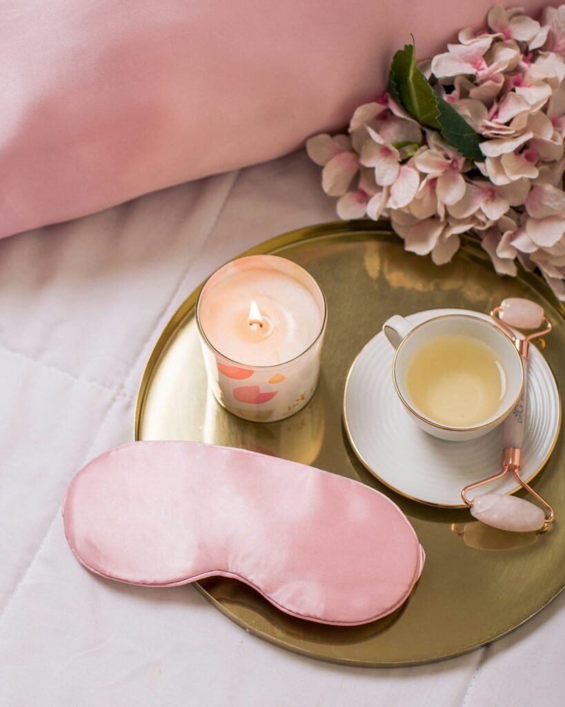 A small glass essential oil bottle and a soft sleep eye mask resting on a hotel nightstand